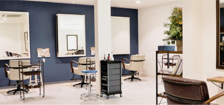 白い壁と青いアクセントカラーの壁に鏡と椅子が並んでいる様子